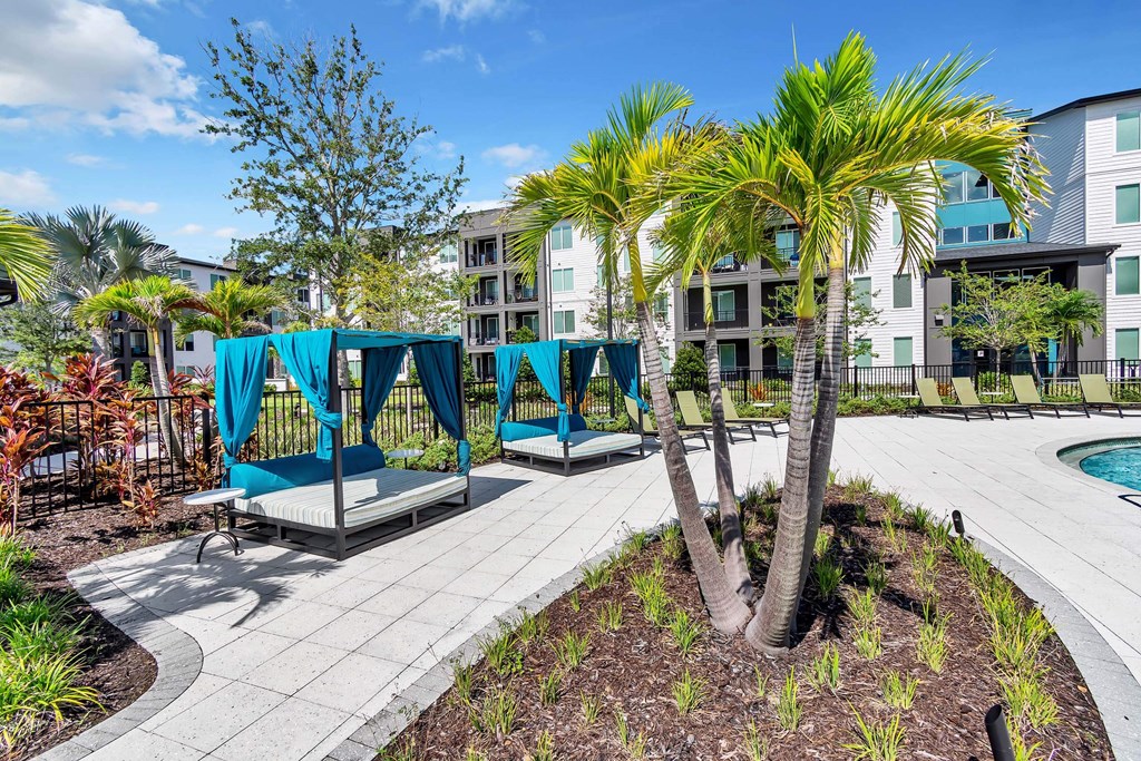 a patio with lounge chairs and a pool in front of an apartment building