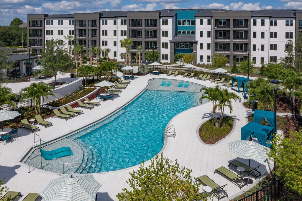 an aerial view of the resort style pool with lounge chairs and umbrellas