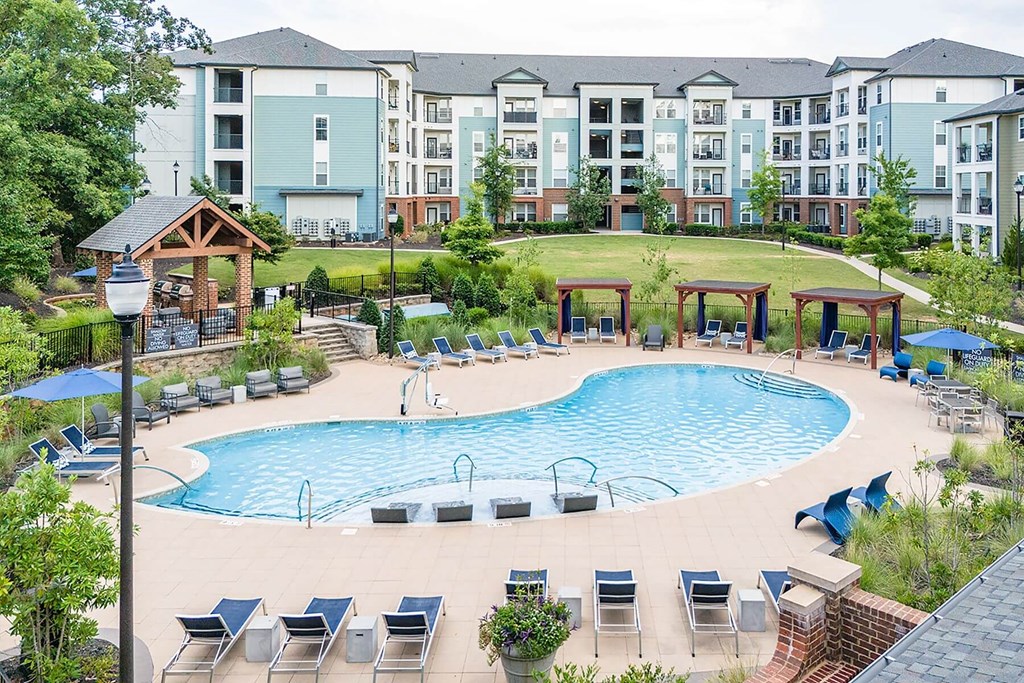 an outdoor pool with chairs around it and an apartment building