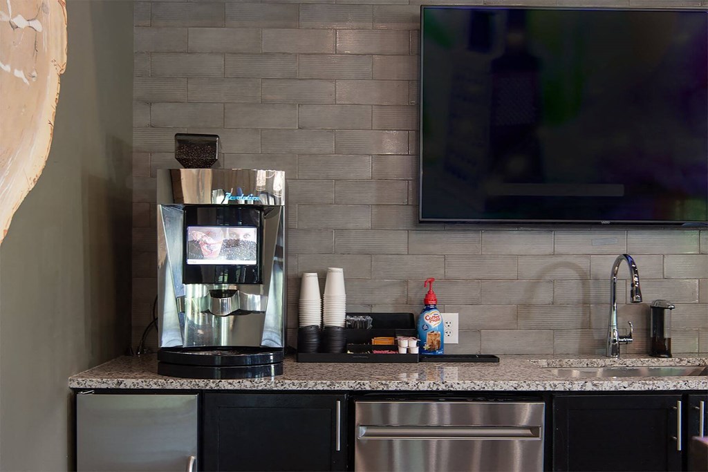 a clubhouse kitchen with a coffee maker and a counter with a sink