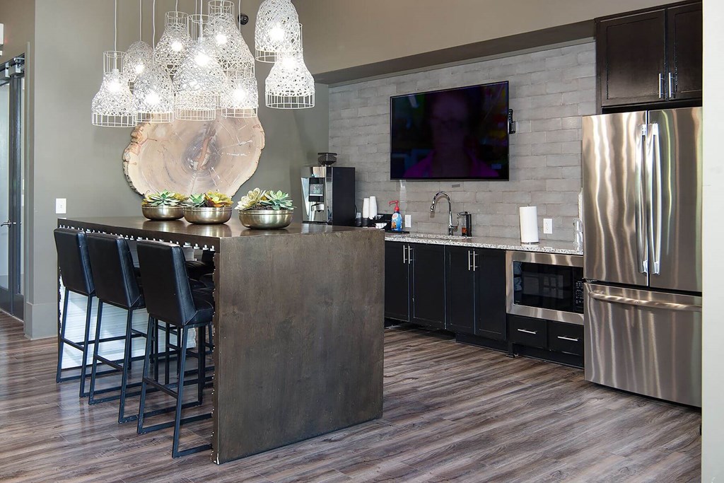 a clubhouse kitchen with stainless steel appliances and a bar with chairs
