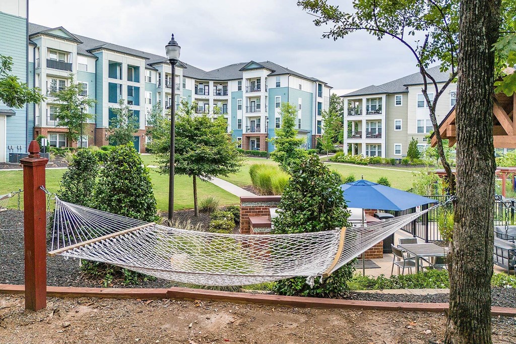 a hammock in a park in front of an apartment building