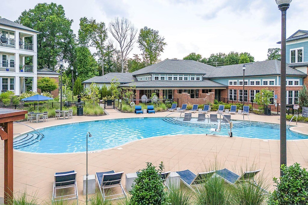 a swimming pool with chairs and a building in the background