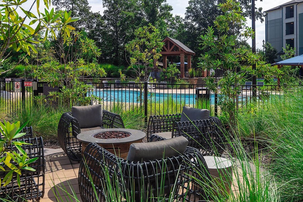 a patio with chairs and a table near a pool