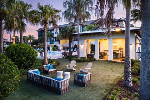 A backyard with a pool and a patio with chairs and a table.