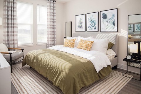 A bedroom with a bed covered in a green comforter and two pillows.