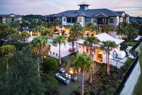 A large house with a pool surrounded by palm trees.