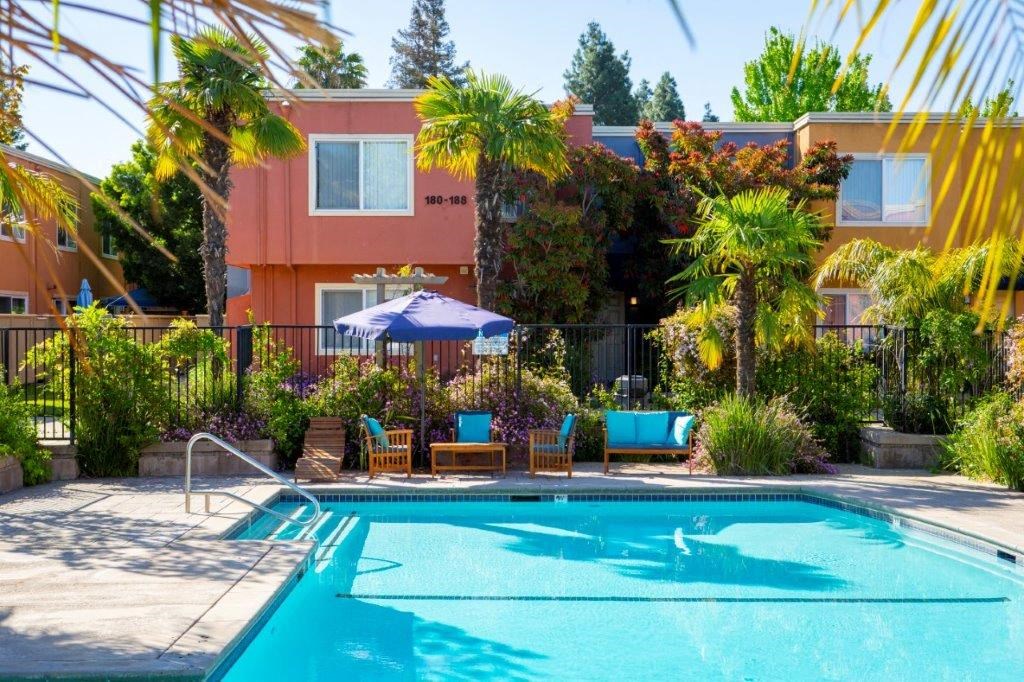 a pool with chairs and an umbrella in front of a building