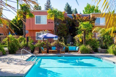 a pool with chairs and an umbrella in front of a building