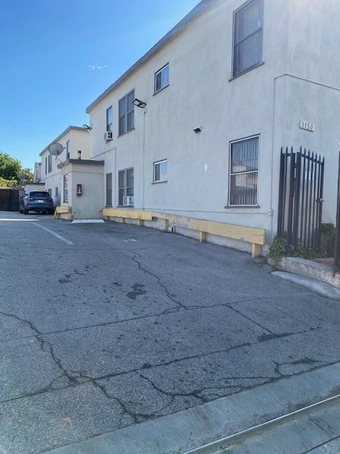 A white building with a black gate on the right side.
