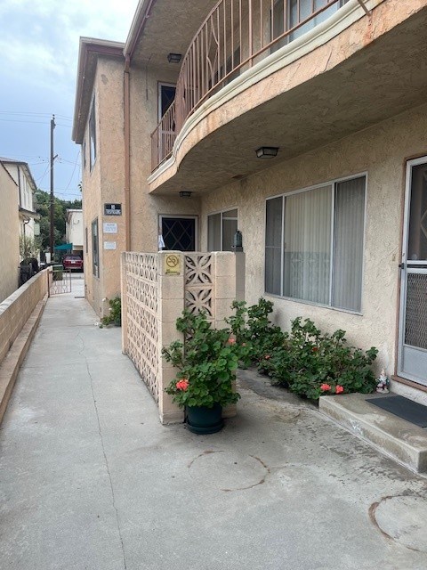 A building with a white fence and a planter with red flowers.