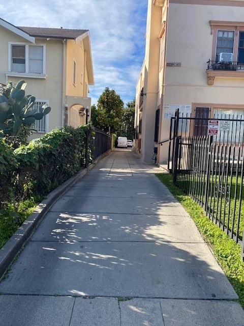 A sidewalk runs down a quiet street between two buildings.