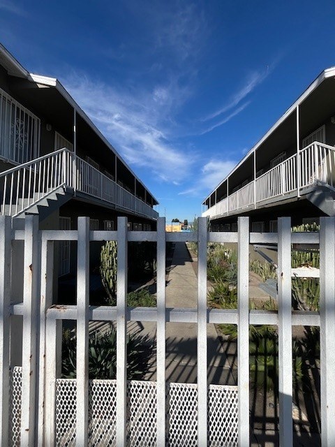 A white fence with lattice panels separates two buildings.