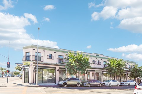 A street view of a building with cars parked in front.