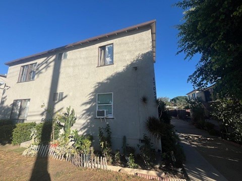 A house with a brown roof and a white wall with a window and a door.