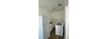 A white kitchen with a refrigerator, stove, and cabinets.