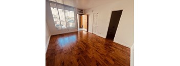 A room with wooden flooring and a door leading to a balcony.