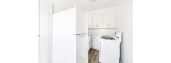 A white kitchen with a refrigerator, oven, and cabinets.