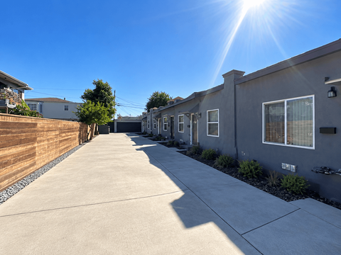 A sunny day in a residential area with houses on both sides of a concrete path.