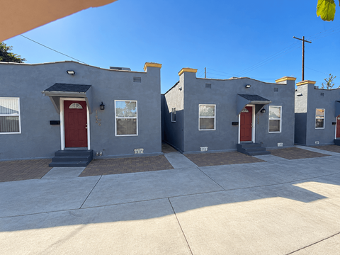 A row of houses with red doors and grey walls.