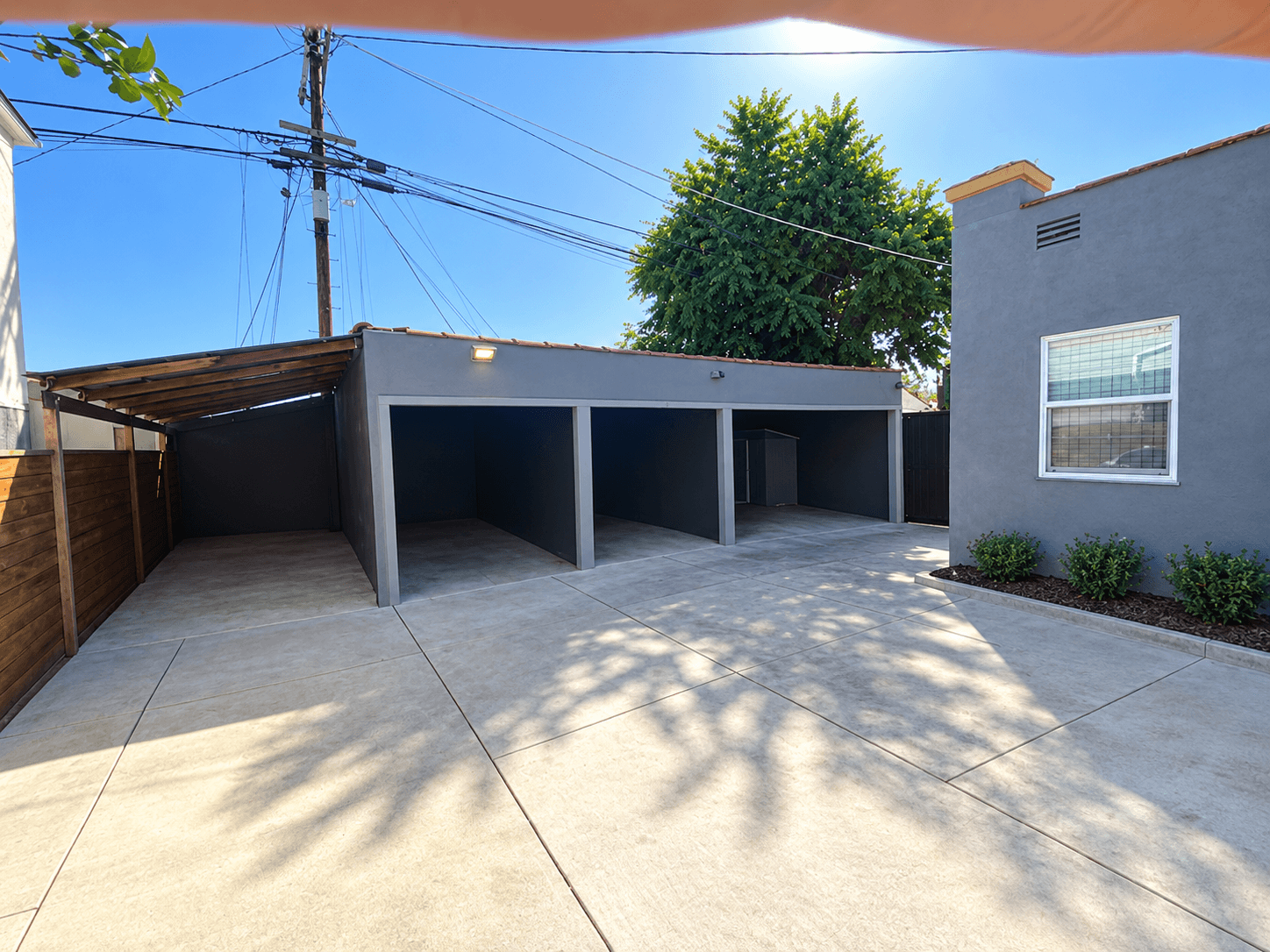 A sunny day with a grey house and a clear blue sky.