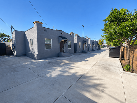A row of grey houses with a tree on the right side.