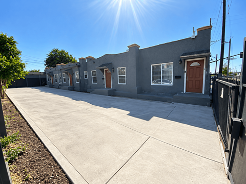 A sunny day in front of a grey building with a brown door.