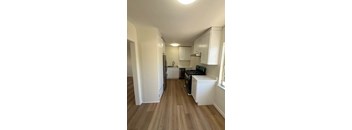 A kitchen with white cabinets and a wooden floor.