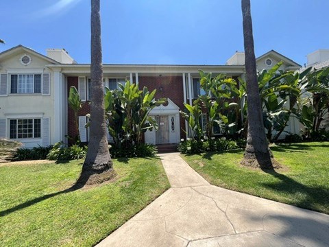 A white house with a brown roof and a white fence.