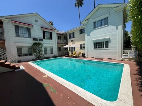 A swimming pool in front of a white building.