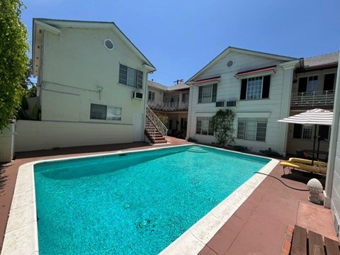A swimming pool in a backyard surrounded by houses.