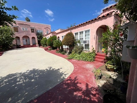 A red brick pathway leads to a white door in a courtyard.