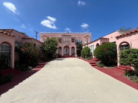 A long driveway leads to a building with arched windows.