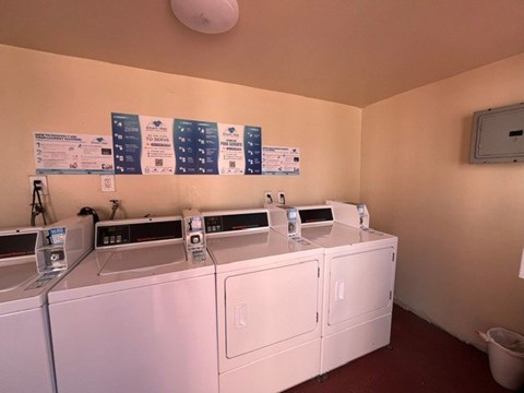 A laundromat with washers and dryers and signs on the wall.