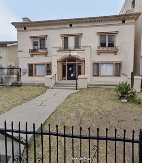 A beige house with a black fence in front.