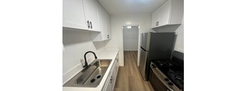A kitchen with white cabinets and a stainless steel refrigerator.