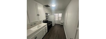 A small kitchen with white cabinets and a black stove top oven.