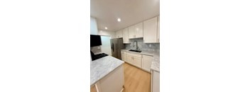 A kitchen with white cabinets and a marble countertop.