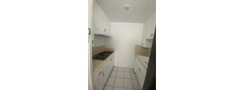 A kitchen with white cabinets and a tiled floor.