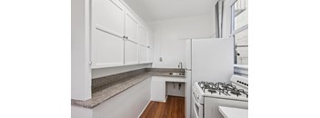 A kitchen with white cabinets and a white stove.