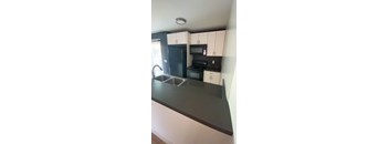 A kitchen with black countertops and white cabinets.