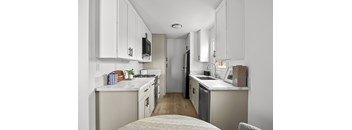 A kitchen with white cabinets and a wooden floor.