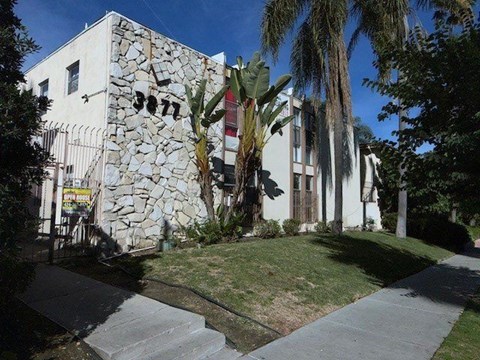 A white building with a stone wall on the side.