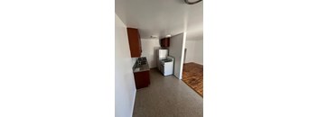 A kitchen area with a white fridge and a sink.