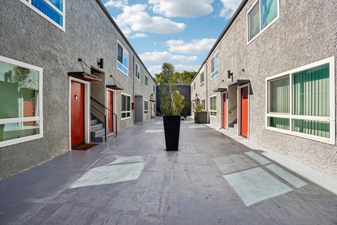 A long concrete walkway between two buildings with windows and doors.