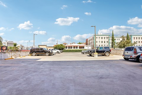 A parking lot with several cars and a building in the background.