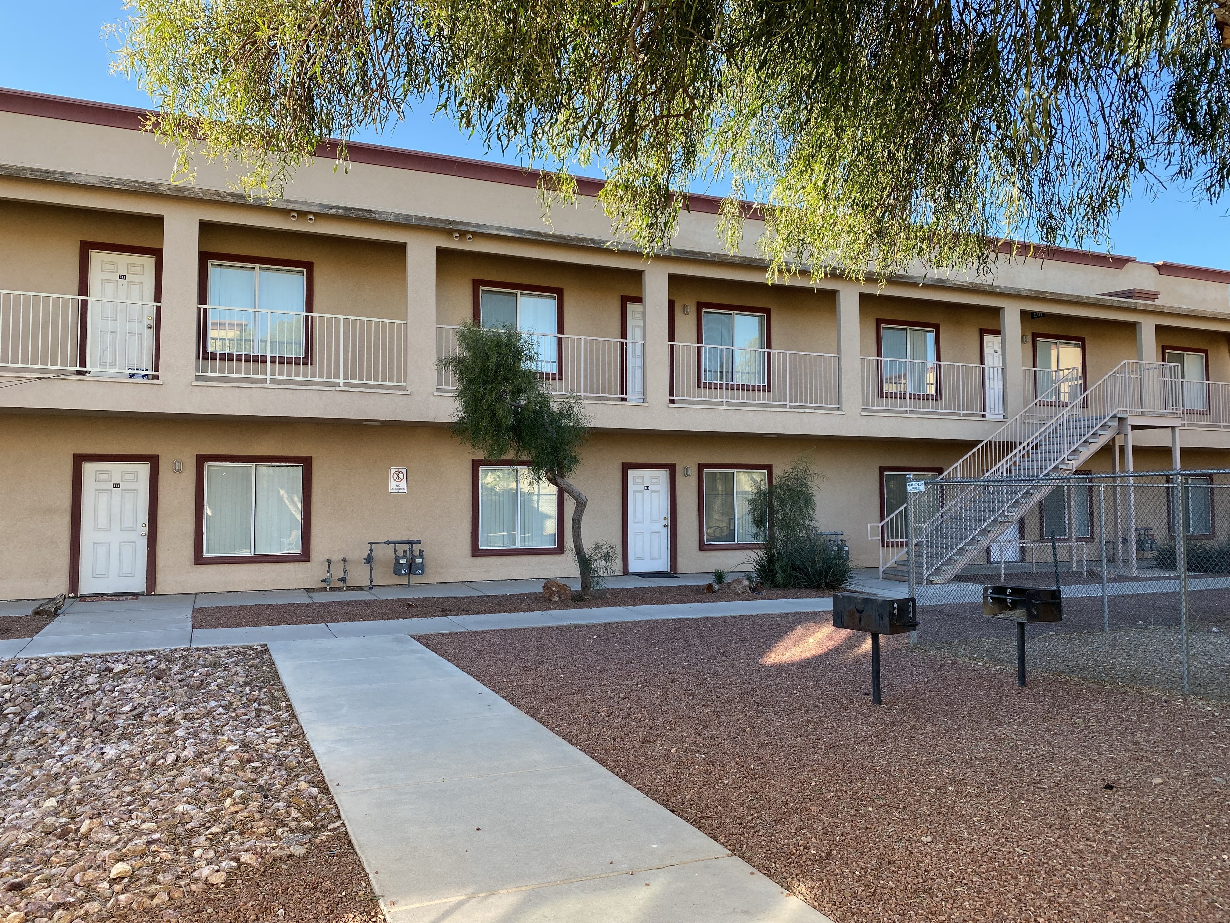 Apartment complex with a tree in front and a staircase leading to the second floor.
