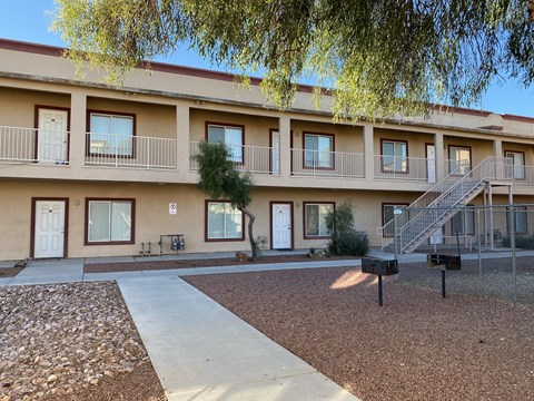 Apartment complex with a tree in front and a staircase leading to the second floor.