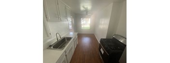 A kitchen with a stove, sink, and cabinets.