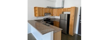 A kitchen with a granite counter top and wooden cabinets.